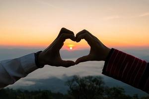 silhuett av bröllop par i kärlek hand tecken hjärta under soluppgång med morgon- himmel bakgrund. före bröllopet porträtt Lycklig par bilder man och kvinna med himmel natur bakgrund. foto