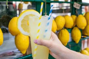 kaukasisk hand med frisk färsk lemonad under sommaren - citron bakgrund foto