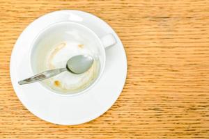 topp se av färga av kaffe i vit koppar och kaffe sked med fat på trä- tabell. foto