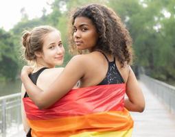 två lesbisk människor vänskap med regnbåge stolthet flagga. glad Gay person har roligt tillsammans med jämlikhet respekt till kärlek och frihet livsstil. mångfald av ung homosexuell par, lgbtq rättigheter. foto