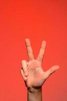 manlig hand är som visar tre fingrar isolerat på röd bakgrund foto