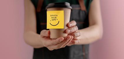 lycka sinne, mental hälsa, njuter liv begrepp. Barista ger en varm kopp av kaffe till kund med positiv notera. Start en trevlig dag. främre se foto