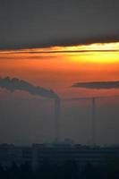 rök kommande från fabrik skorsten på solnedgång foto