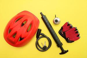 cykel Tillbehör - hjälm, klocka, låsa med nycklar, handskar, pump på en gul bakgrund foto