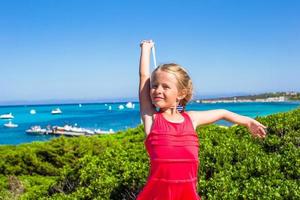 liten förtjusande flicka njuter skön se av turkos hav på de ö av sardinien foto