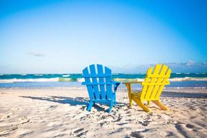 två trä- stolar, gul och blå på en vit sandig strand, mexico foto