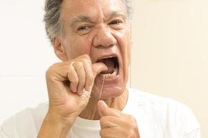 senior man tandtråd hans tänder med dental flock foto