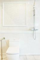 badrumsinredning med dusch, varmvattenberedare och toalett på vit kakelvägg foto