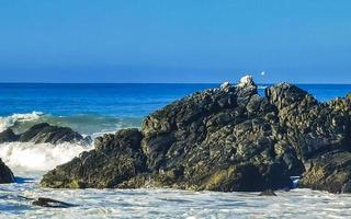 skön stenar klippor surfare vågor på strand puerto escondido Mexiko. foto