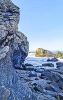 skön stenar klippor surfare vågor på strand puerto escondido Mexiko. foto