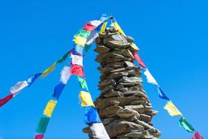 färgrik tibetan buddist bön flaggor hängande på en sten lugg o foto