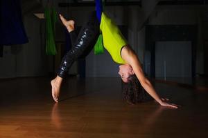 Söt flicka praxis antigravitation yoga placera i Gym på en blu foto