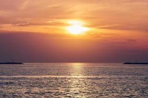 lugnt hav med solnedgångshimmel, vacker panoramautsikt, fantastisk dramatisk uppgående sol som reflekteras i vatten foto