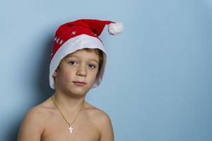 söt europeisk pojke i en st. nicholas hatt på en blå bakgrund, jul. glad jul foto