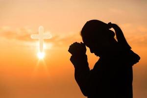 tro av kristen begrepp. andlig bön händer över Sol glans med suddig skön solnedgång bakgrund. kvinna händer dyrkan Gud med kärlek och tro. silhuett av en kvinna bön- med en korsa. foto