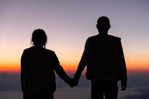 silhuett av bröllop par i kärlek innehav hand tillsammans under soluppgång med morgon- himmel bakgrund. före bröllopet porträtt. Lycklig par bilder man och kvinna med himmel natur bakgrund foto