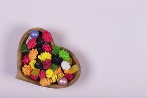 färgrik sötsaker och godis är hällde in i en hjärtformade trä- vas. foto
