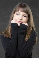porträtt av en skön fundersam flicka av tio år gammal på en grå bakgrund. foto