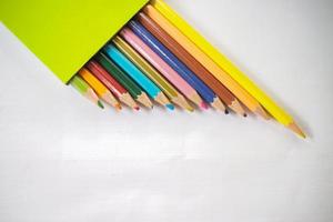 färgad pennor ordentligt fodrad upp på vit papper, där är skärpare och löv foto