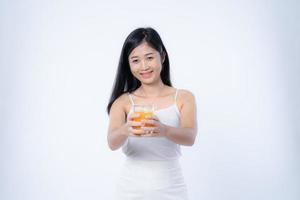 skön asiatisk kvinna dricka orange juice, sjukvård, hud, skönhet och välbefinnande koncept, isolerat på vit bakgrund foto