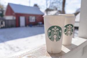 marinette, wi, usa - 14 nov, 2023- koppar av starbucks varm kaffe sätta på vit snö i vinter- trädgård, färsk och varm dryck ta bort concept.starbucks Kafé kaffe affär. foto