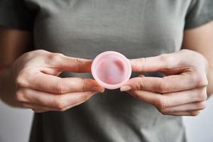 kvinna innehar menstruations- kopp i händer foto