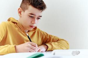Tonårs pojke skriva läxa på Hem. utbildning begrepp foto