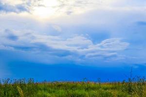 grön fält landskap med blå himmel och stormig moln. foto