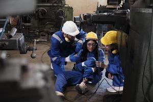 smärtsam olycka i industriell produktion metallarbete, afrikansk amerikan kvinna arbetstagare skadade henne ben, manlig ingenjör och kollega team hjälpte först hjälpa med vård på tillverkning maskineri fabrik. foto