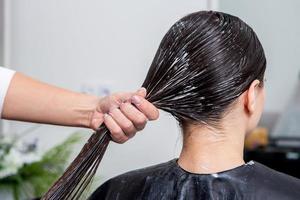 frisör gäller en hår mask till hetero svart hår. hår vård på de skönhet salong. foto