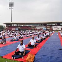 ny delhi, Indien, juni 21 2022 - grupp yoga övning session för människor på yamuna sporter komplex i delhi på internationell yoga dag, stor grupp av vuxna delta yoga klass i cricket stadion foto