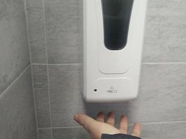 använder sig av de tvätta hand desinfektionsmedel gel pump dispenser. personlig hygien begrepp. coronavirus pandemi förebyggande döda virus med hand sanitizer. foto