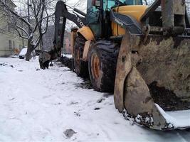 sankt petersburg ryssland - 02 02 2023 stor orange traktor rengör upp snö från de väg och massor den in i de lastbil. rengöring och rengöring av vägar i de stad från snö i vinter. foto