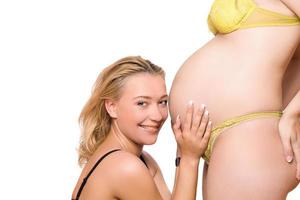 leende kvinna och mage av gravid flickvän foto