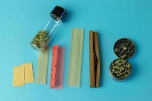 rökning marijuana Tillbehör platt lägga på blå bakgrund. topp se av cannabis knoppar, gemensam och trubbig papper foto