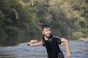 asiatisk Pojkar är utgifterna deras lediga tider förbi dykning, simning, kasta stenar och fångst fisk i de flod tillsammans lyckligt. hobby och lycka av barn begrepp. foto