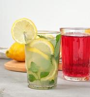 citronsaft med citroner, mynta löv, kalk i en glas och röd bär citronsaft foto