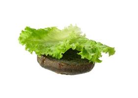 grön sallad blad lögner på en halv av en svart runda bulle foto