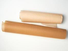 två rullar av brun pergament papper för bakning på en vit bakgrund foto