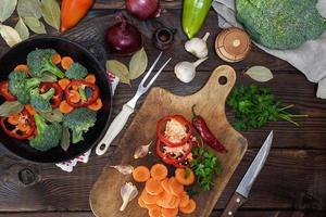 färsk bitar av morötter, broccoli och röd peppar på en trä- kök styrelse foto