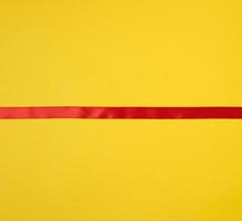 röd silke band på en gul bakgrund, festlig bakgrund foto