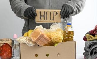 samlar mat, frukt och saker i en kartong låda till hjälp de behövande och de fattig foto