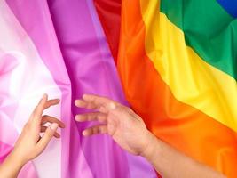 kvinna och manlig hand utsträckt mot de bakgrund av flaggor av HBTQ samhällen foto
