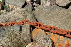 järn rostig fartyg kedja i de mitt ibland av stenar foto