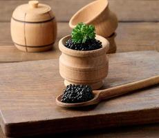 svart kaviar i en trä- tallrik på de tabell foto