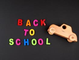 inskrift tillbaka till skola från flerfärgad plast brev och trä- bebis bil på svart krita styrelse foto