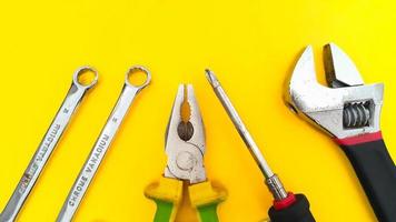 verktyg uppsättning av rycka, justerbar skiftnyckel, tång och skruvmejsel isolerat på gul bakgrund foto