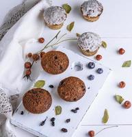 runda bakad muffins med russin på en vit trä- styrelse foto