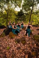 en grupp av asiatisk kvinnor tar en semester till de skog medan bär en grön kjol och Sammanträde på en sten foto