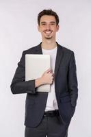 porträtt av ung affärsman Lycklig positiv leende innehav bärbar dator isolerat över vit bakgrund foto